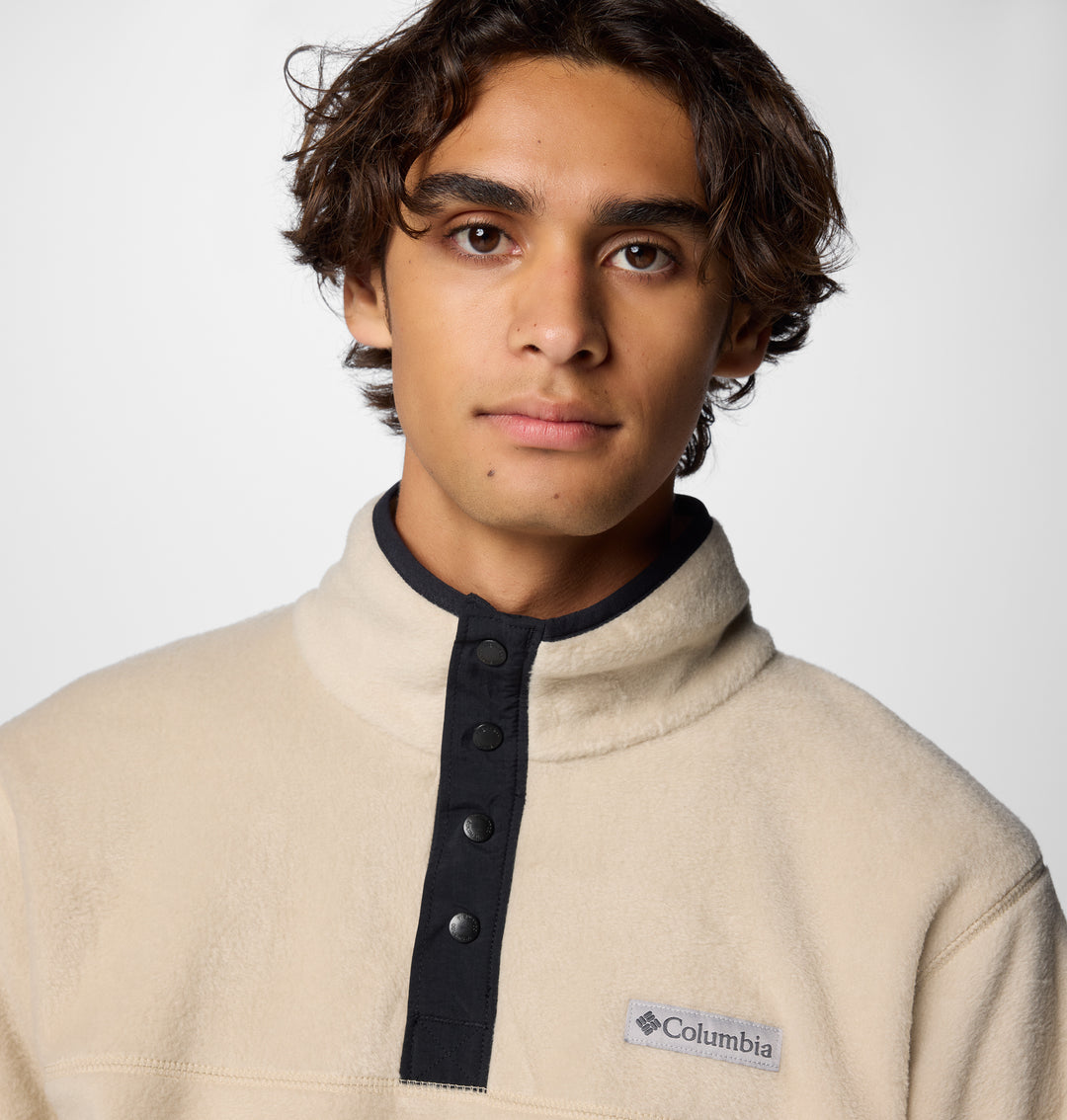 Men's fleece pullover close-up: black half-snap placket and Columbia logo patch on beige