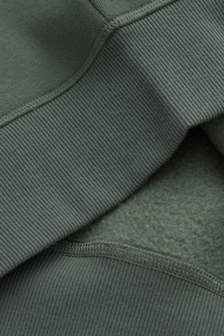 Green hoodie close-up showing ribbed seam and soft fleece lining