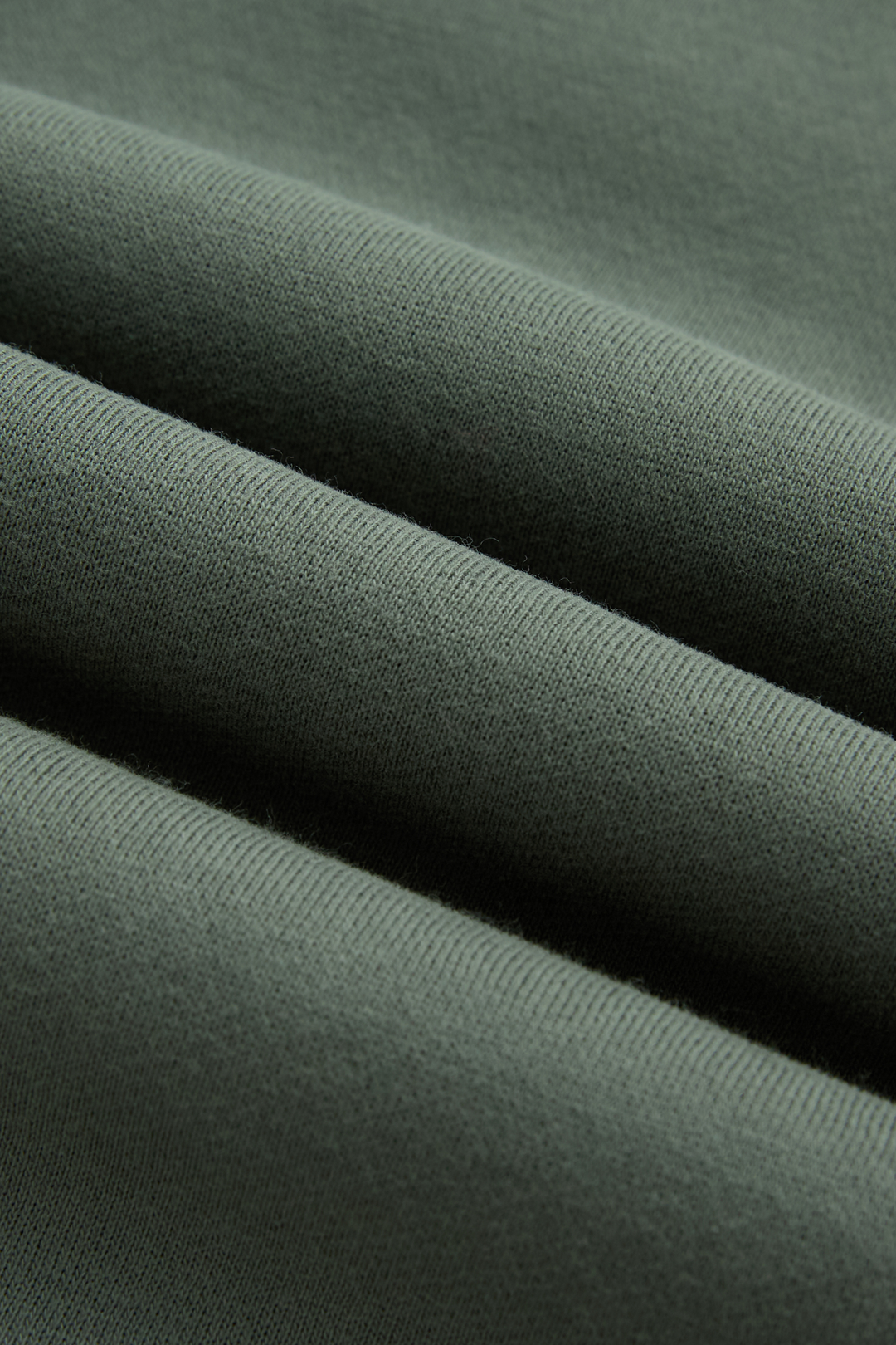 Green hoodie fabric close-up showing its soft knit texture