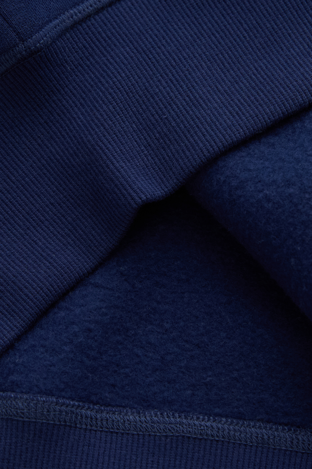 Navy hoodie fabric close-up showing a soft brushed interior and stitched seam
