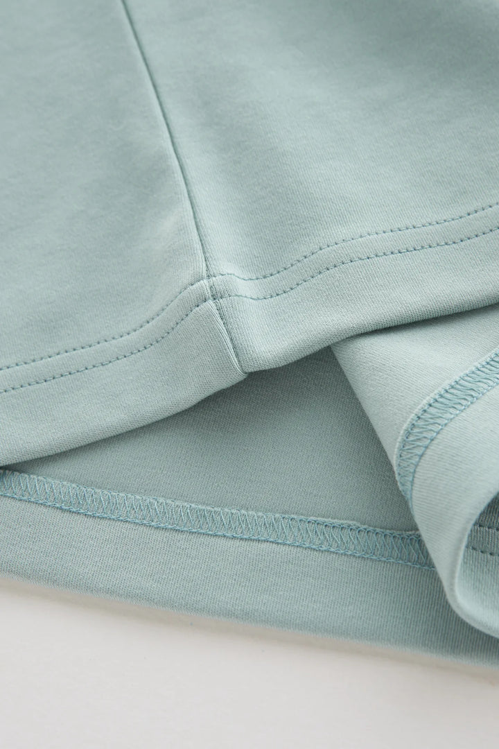 Mist green T-shirt hem with double-stitched seam and overlock edge