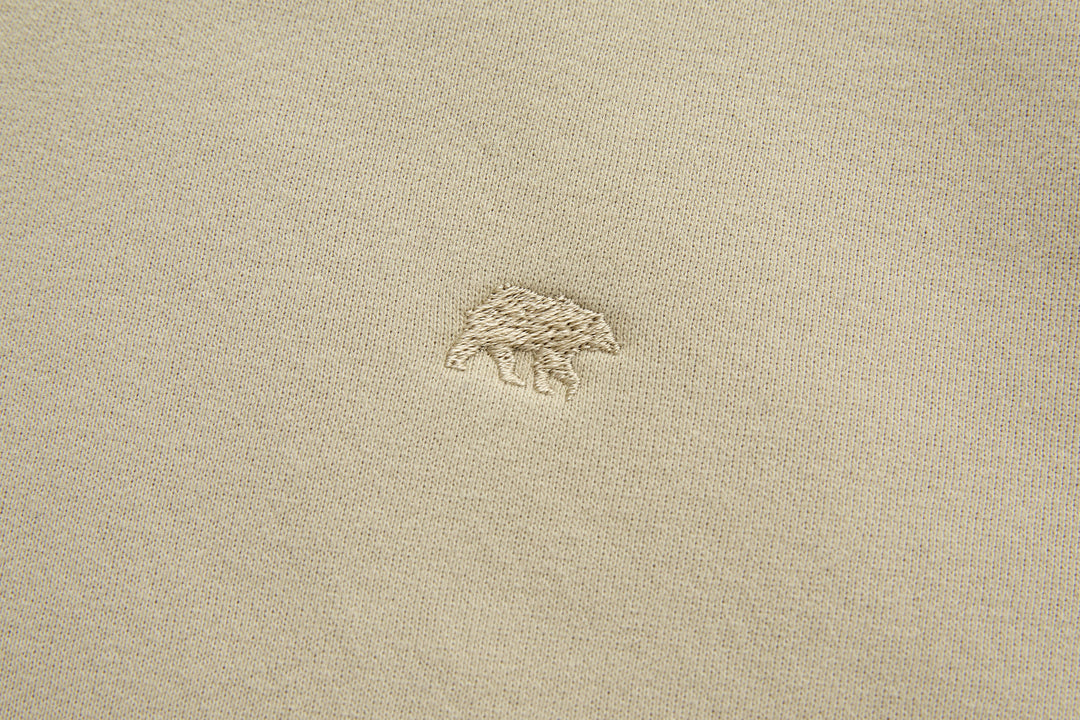 Rivet & Denim hoodie chest logo, small embroidered emblem on light feather beige