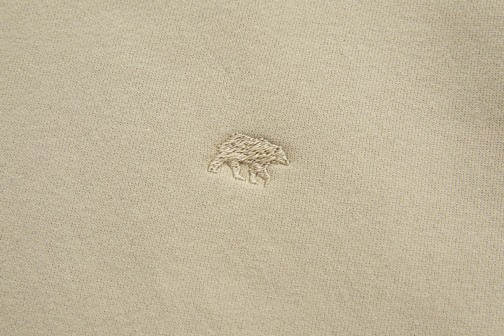 Rivet & Denim hoodie chest logo, small embroidered emblem on light feather beige