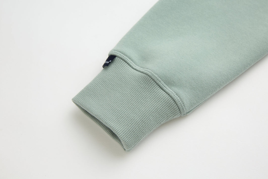 Jade denim hoodie cuff with ribbed knit trim and small inner tag near hem.