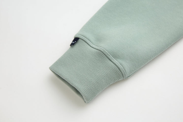 Jade denim hoodie cuff with ribbed knit trim and small inner tag near hem.