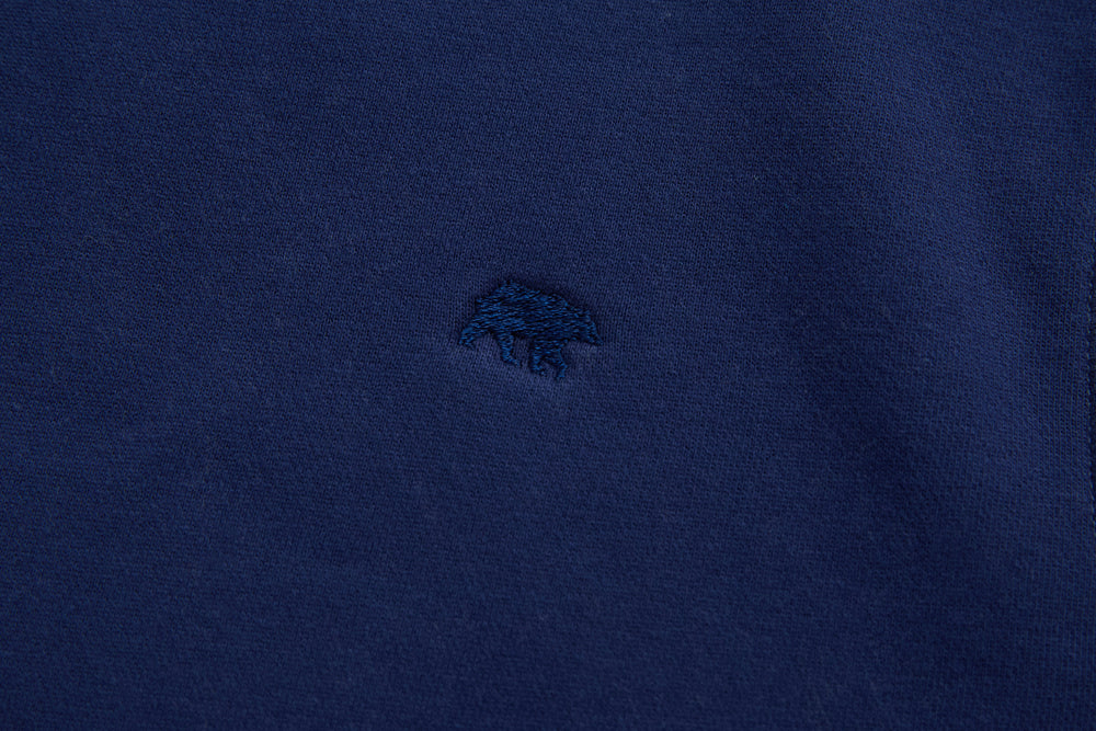 Navy denim hoodie front with small embroidered chest logo