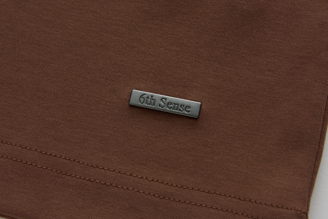 Brown polo shirt with 6th Sense logo label near the hem