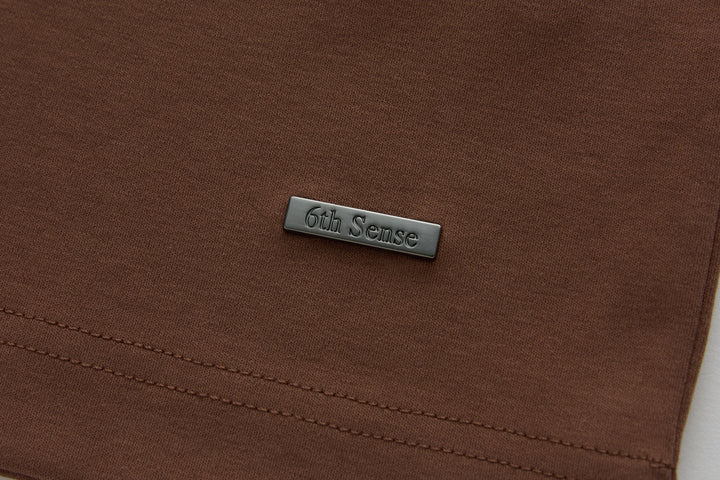 Brown polo shirt with 6th Sense logo label near the hem