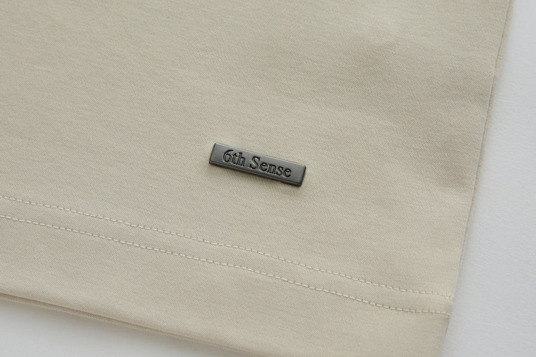 Cream polo shirt with 6th Sense logo badge on the front