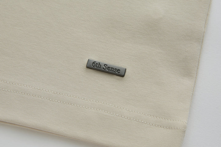 Cream polo shirt with 6th Sense logo badge on the front