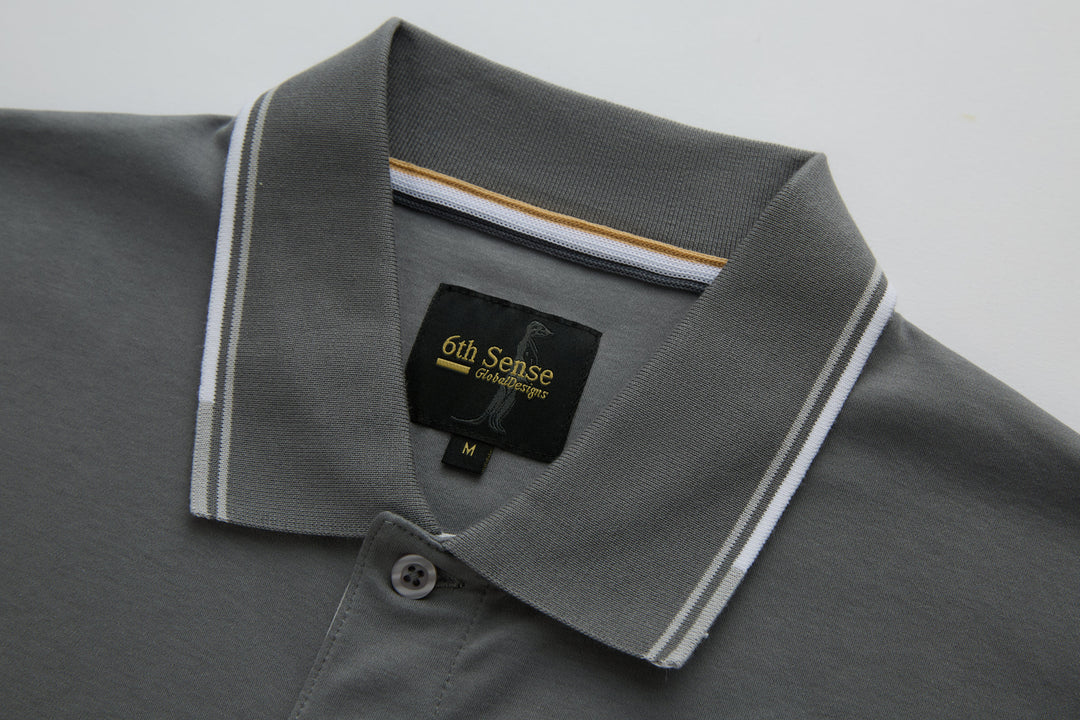 Gray polo shirt collar with striped trim and 6th Sense logo patch.