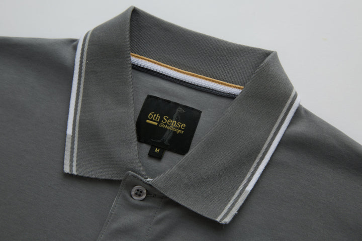 Gray polo shirt collar with striped trim and 6th Sense logo patch.