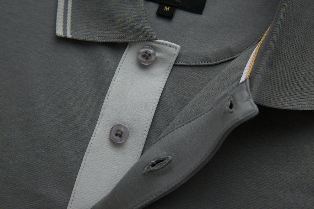 Gray polo shirt placket detail with contrasting inner facing and button.