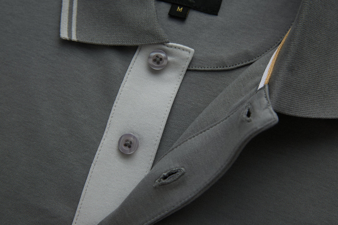 Gray polo shirt placket detail with contrasting inner facing and button.
