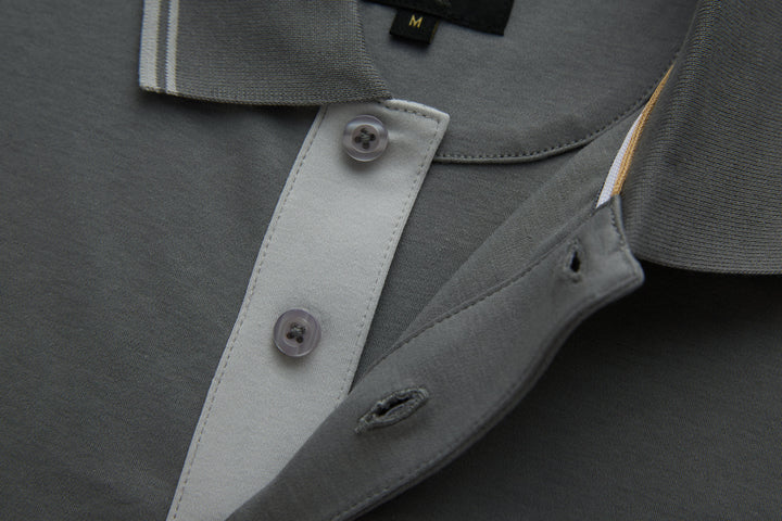 Gray polo shirt placket detail with contrasting inner facing and button.