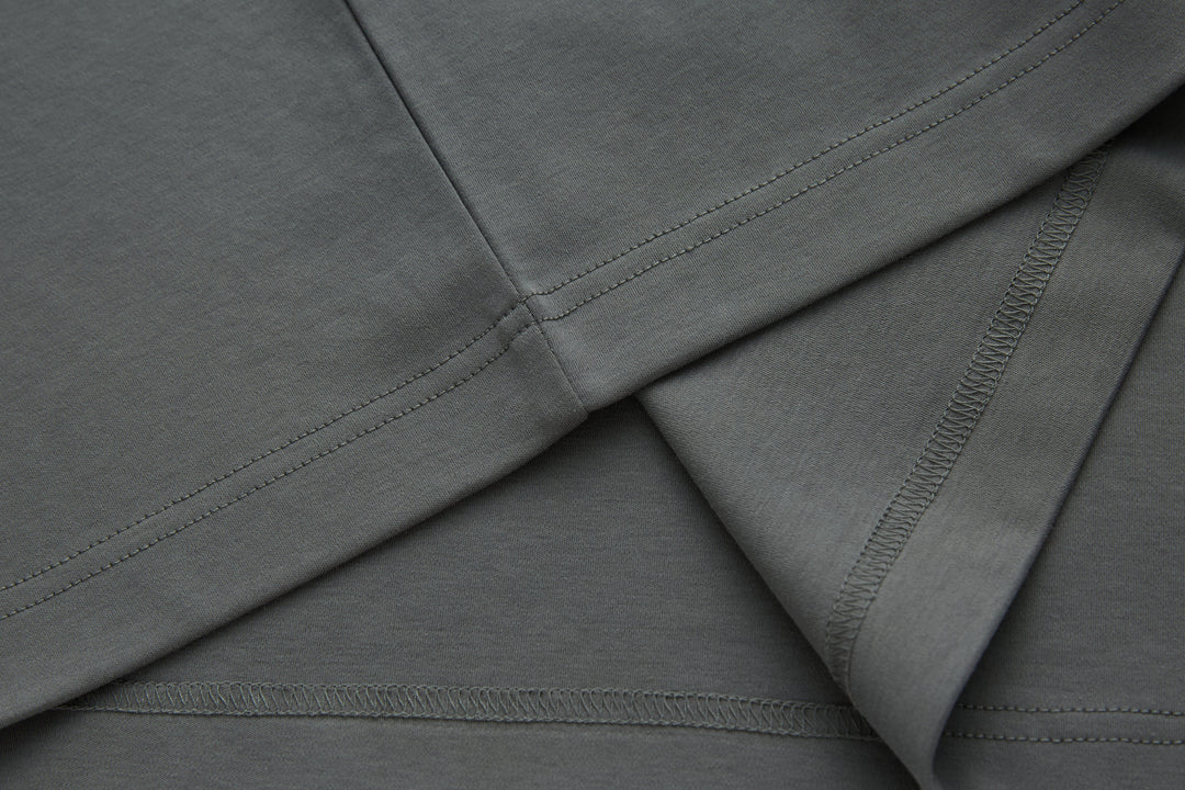 Gray polo shirt sleeve and bottom hem with stitched edging.