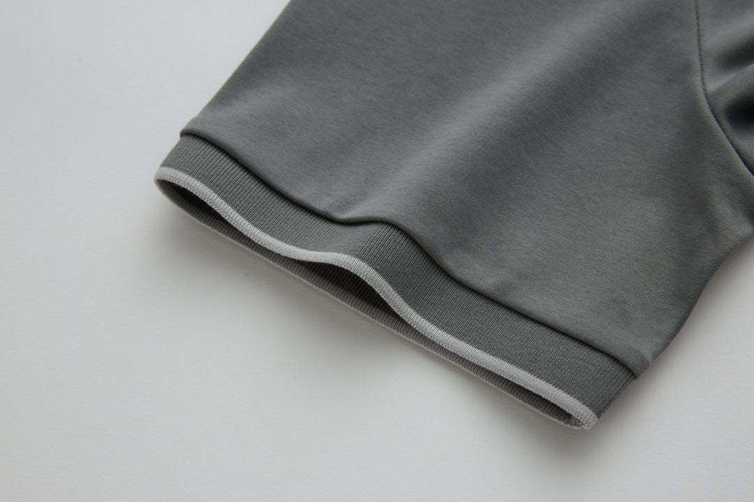 Gray polo shirt sleeve cuff with ribbed trim.