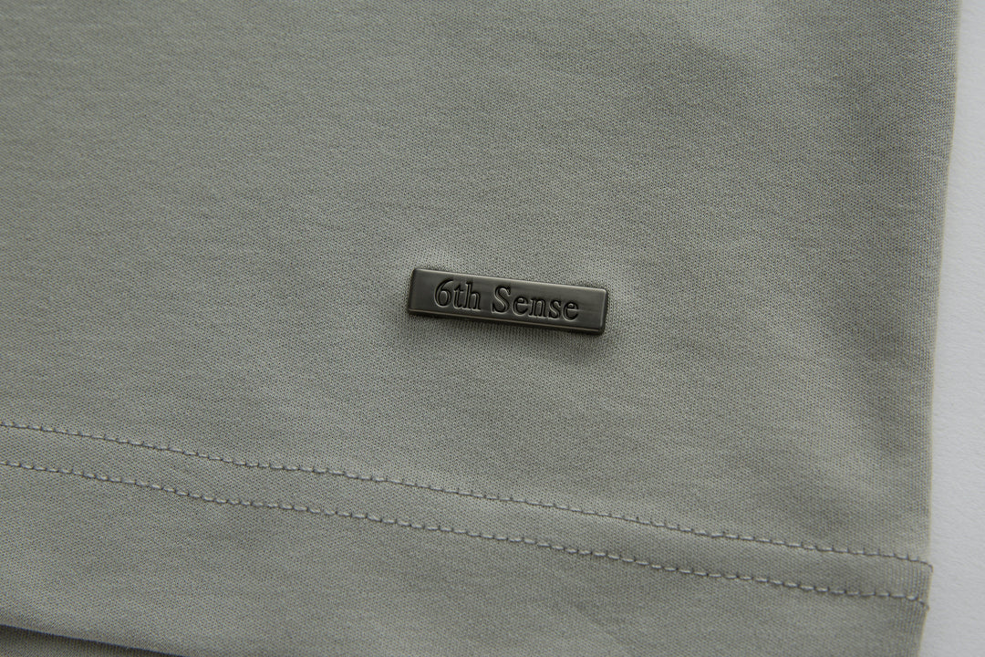 Light gray polo shirt chest with small 6th Sense logo patch