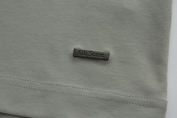 Light gray polo shirt chest with small 6th Sense logo patch
