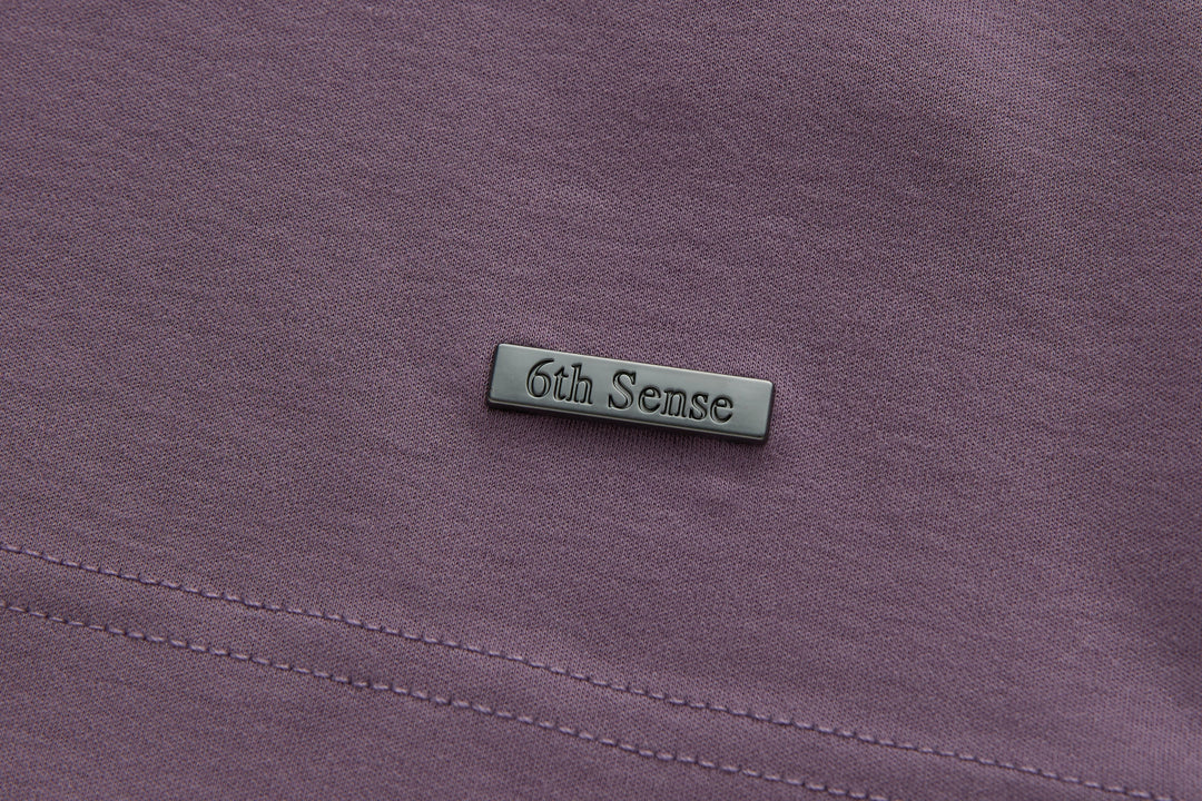 Purple polo shirt chest area with small logo patch and stitched seam