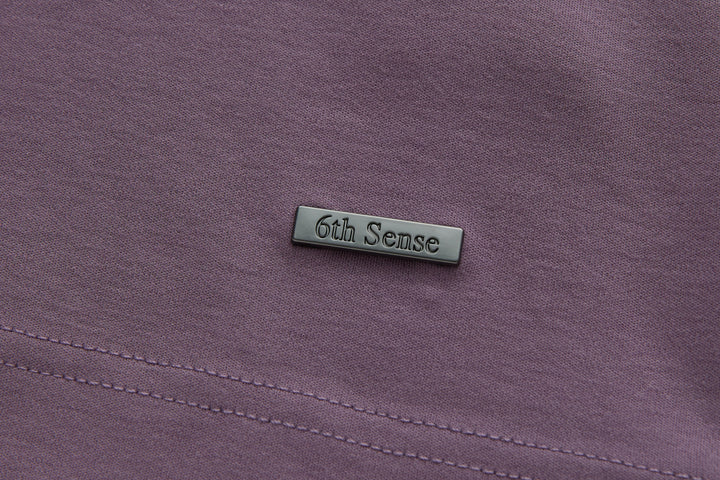 Purple polo shirt chest area with small logo patch and stitched seam