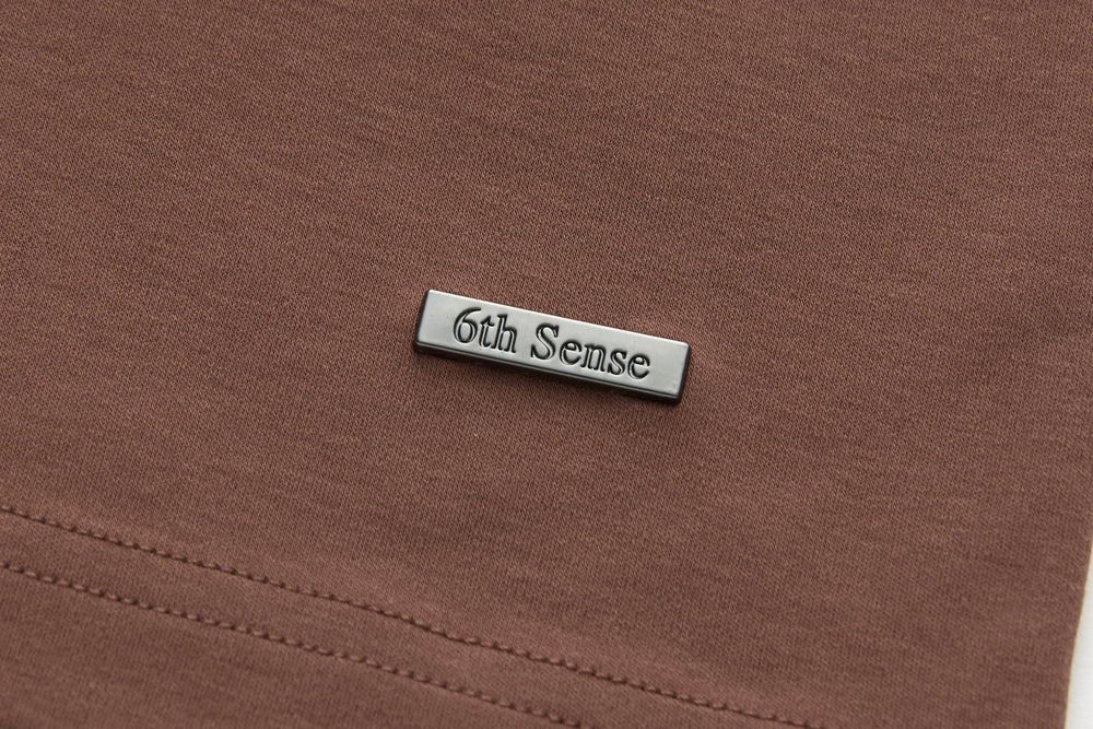 Brown t-shirt with embossed '6th Sense' metal tag at chest
