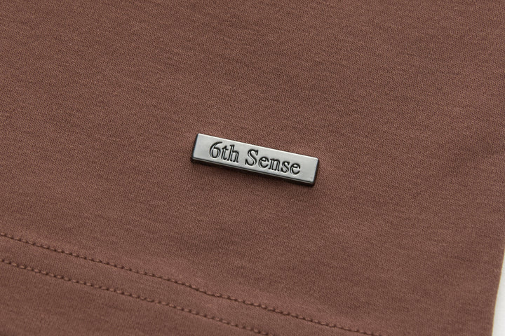 Brown t-shirt with embossed '6th Sense' metal tag at chest