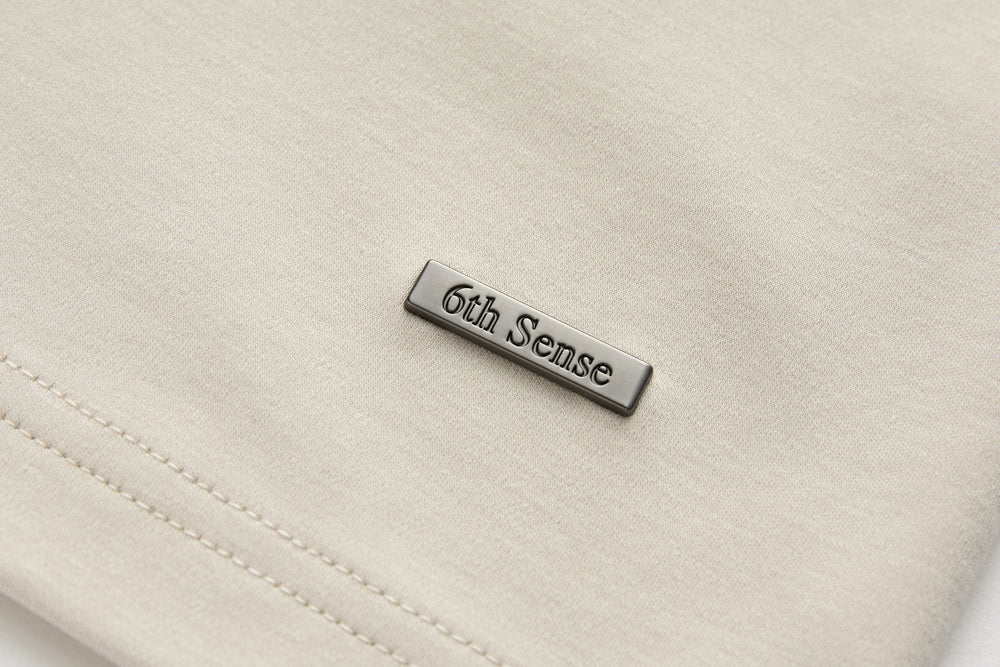6th Sense T-shirt metal logo patch on light cream chest