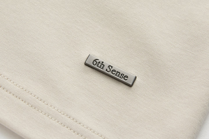 6th Sense T-shirt metal logo patch on light cream chest