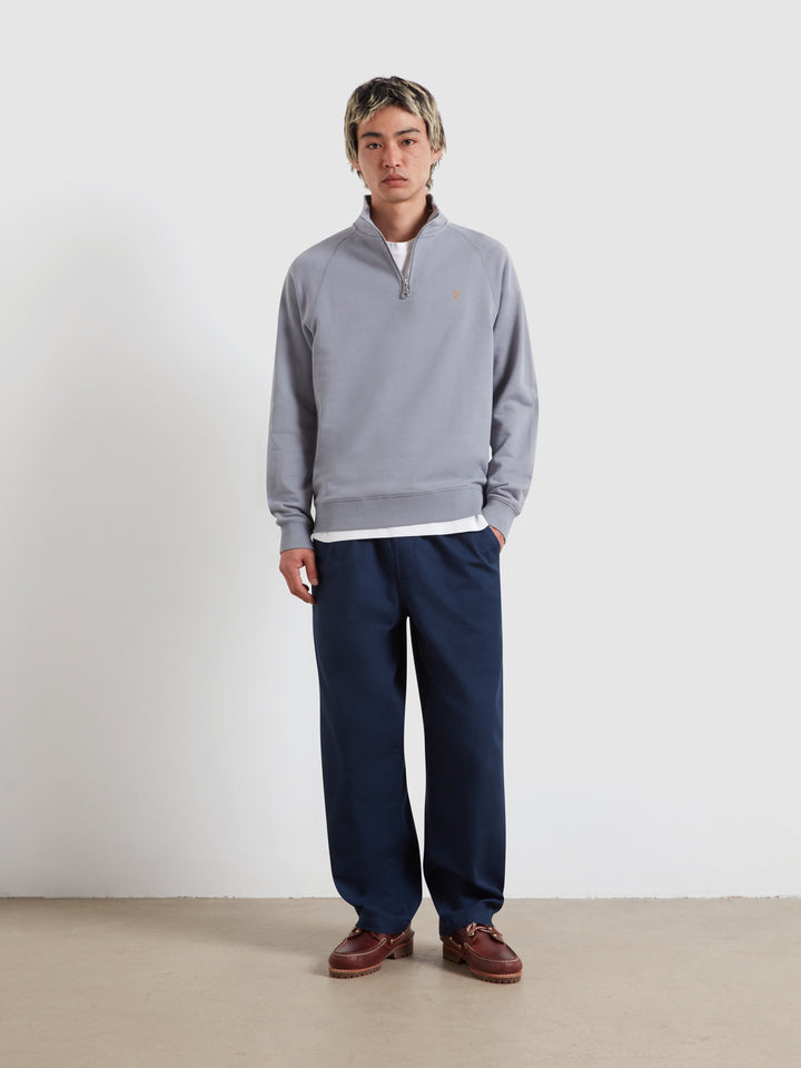 Farah Arnold quarter-zip top with stand collar, light blue; worn with navy trousers