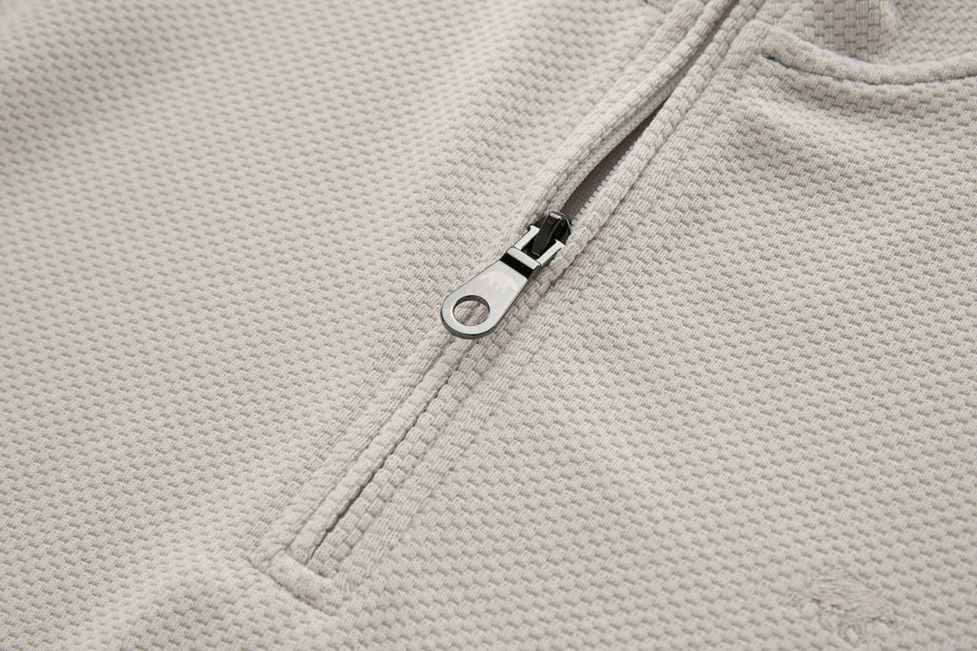 Light beige zipper placket with metal ring pull on 1/4-zip top
