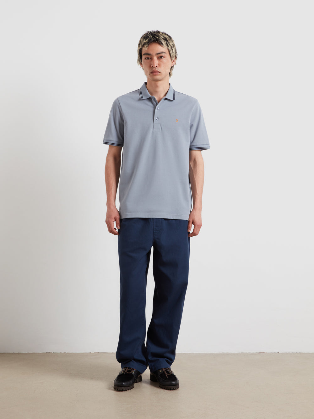 Light blue tipped polo shirt with short sleeves, button placket, and small chest logo