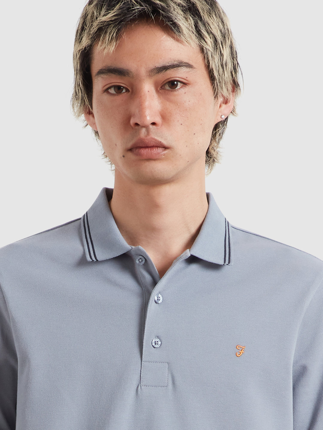 Men's light blue tipped polo shirt with button placket and small orange chest logo