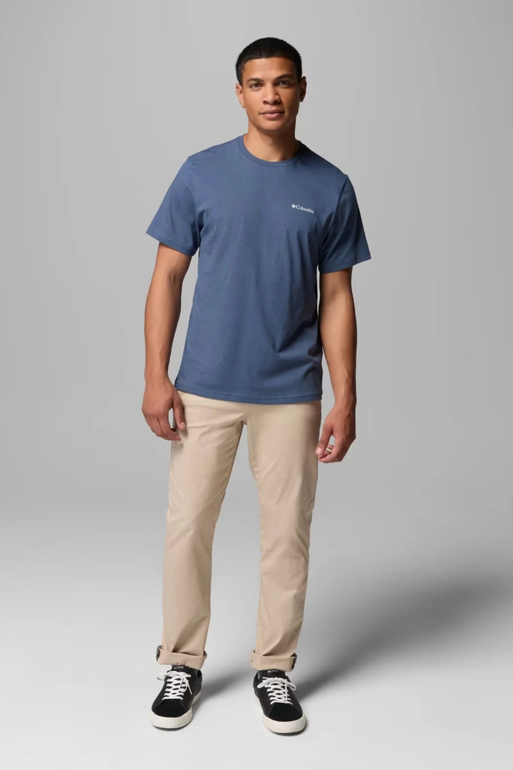 Men's blue graphic logo T-shirt with small chest logo, worn with khaki pants