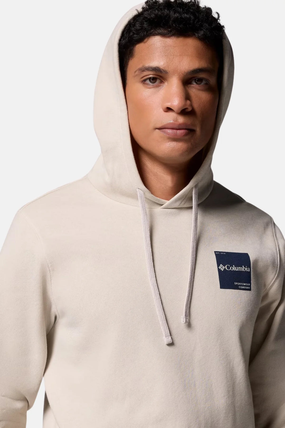 Men's hoodie in light stone with hood drawstrings and chest logo patch.