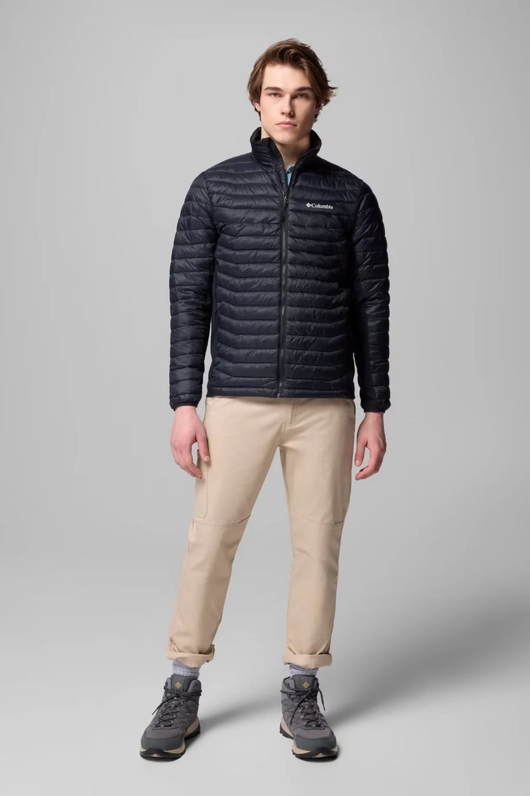 Dark insulated puffer jacket with full-zip front and stand collar, worn with beige pants