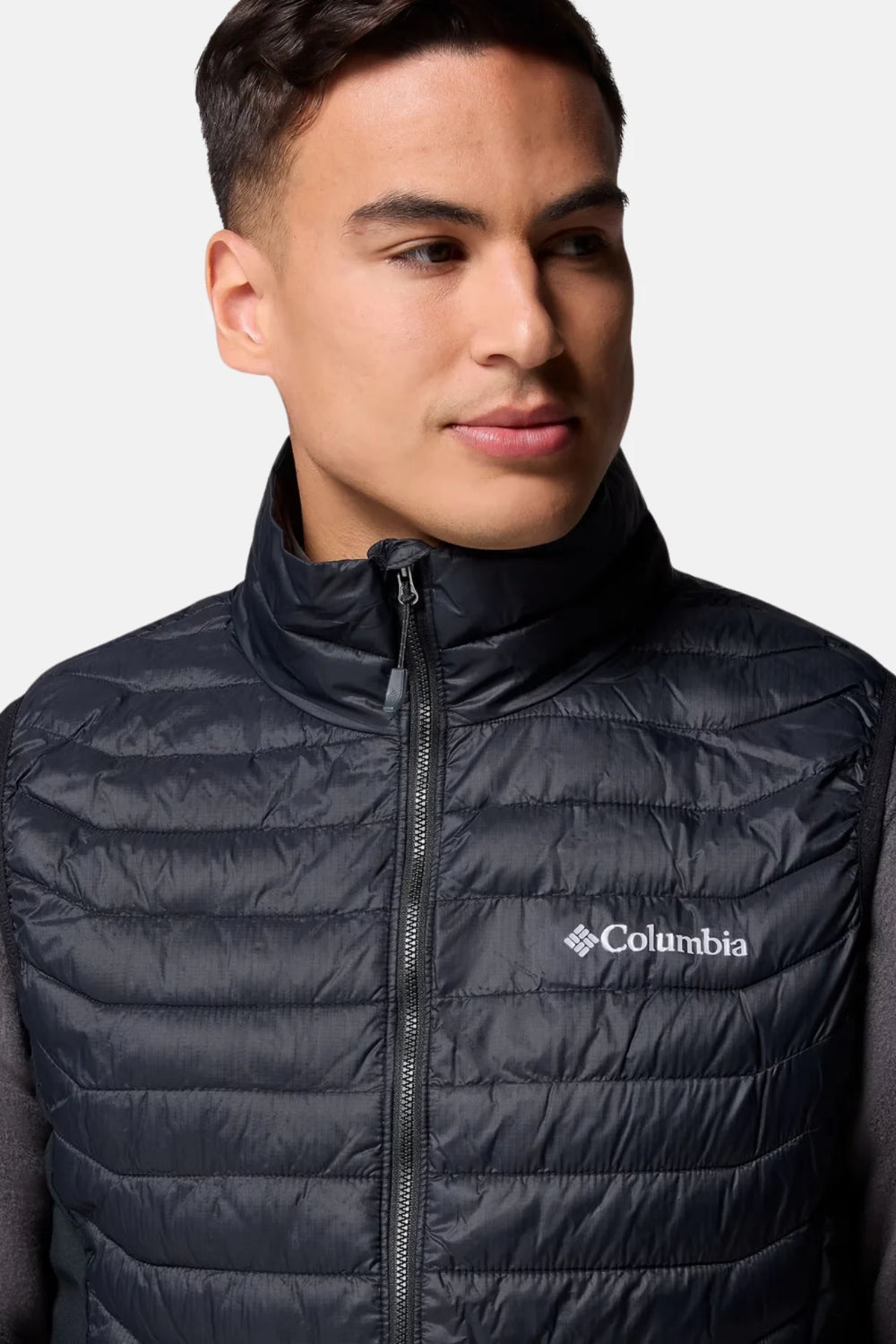 Black puffer vest close-up with zip placket and small Columbia logo on chest
