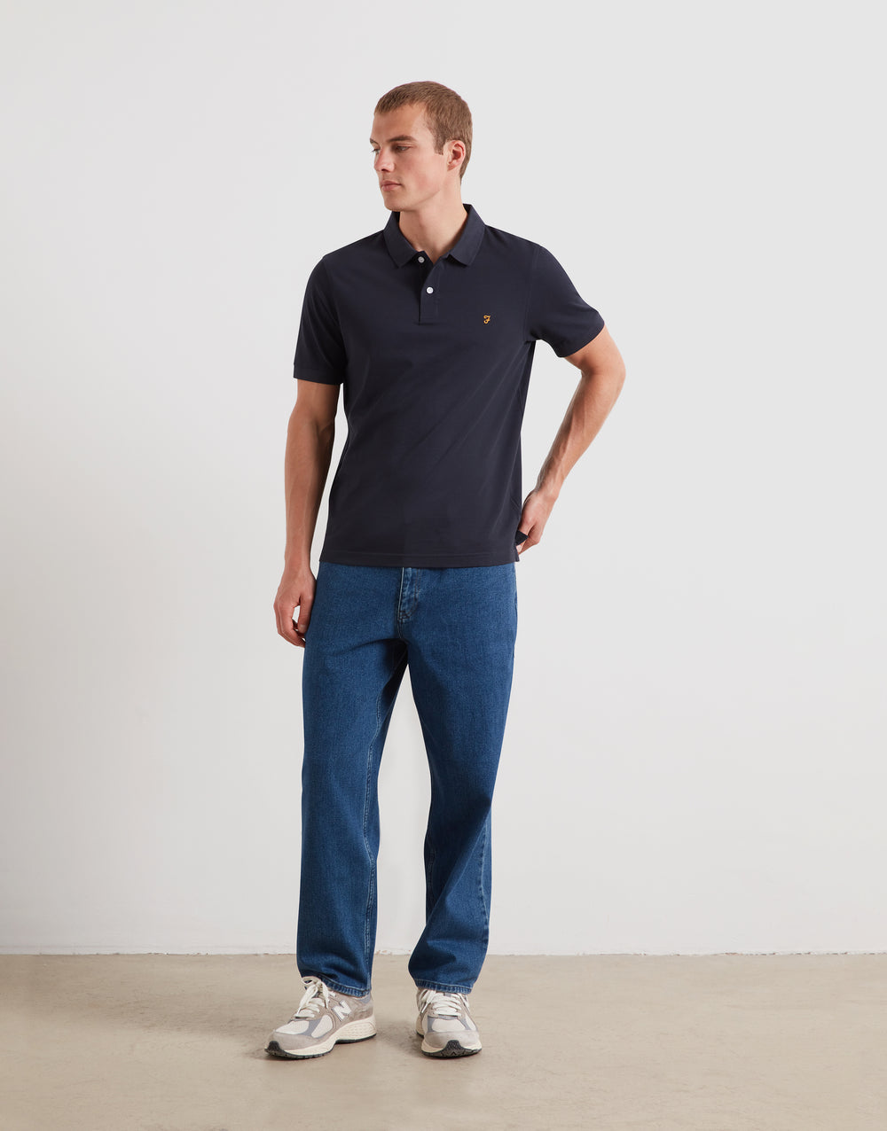 Navy short-sleeve polo shirt with collar and chest logo, worn with jeans