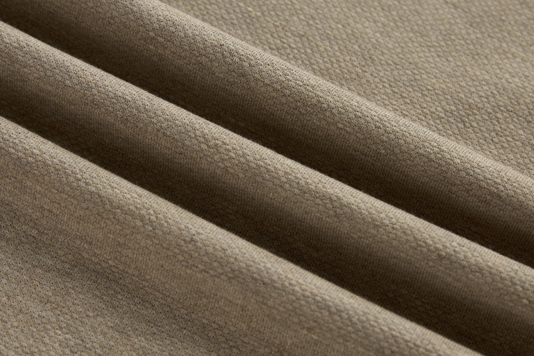 Beige long-sleeve polo shirt fabric close-up with textured knit weave.