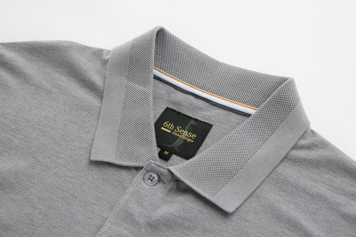 Light gray polo shirt collar with button placket and inner neck label.