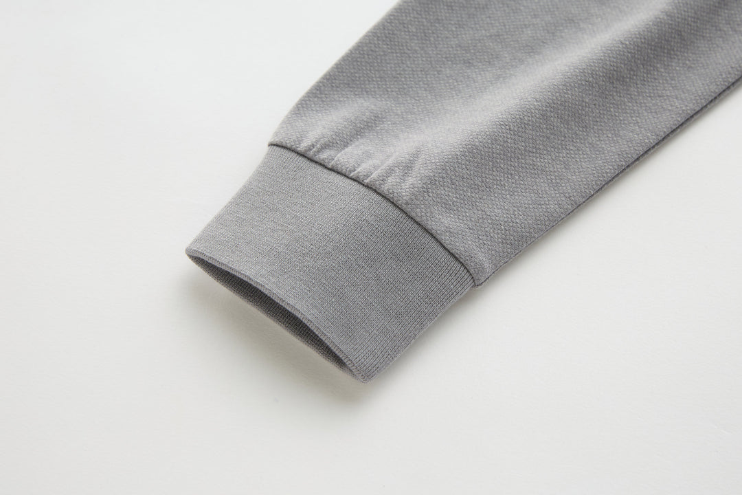 Light gray long-sleeve polo shirt cuff with folded hem.