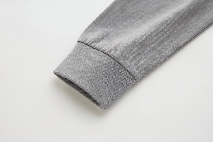 Light gray long-sleeve polo shirt cuff with folded hem.