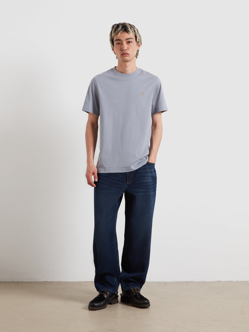 Men's light blue short-sleeve crew-neck T-shirt with chest logo; paired with dark jeans