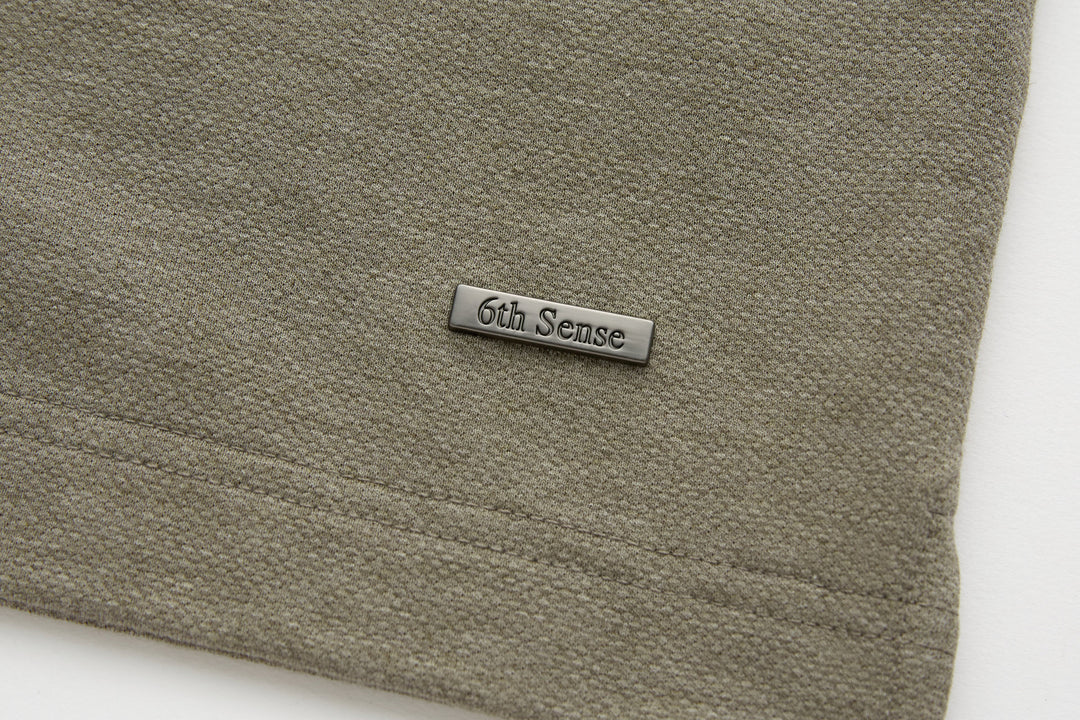 Olive polo shirt hem with 6th Sense logo label