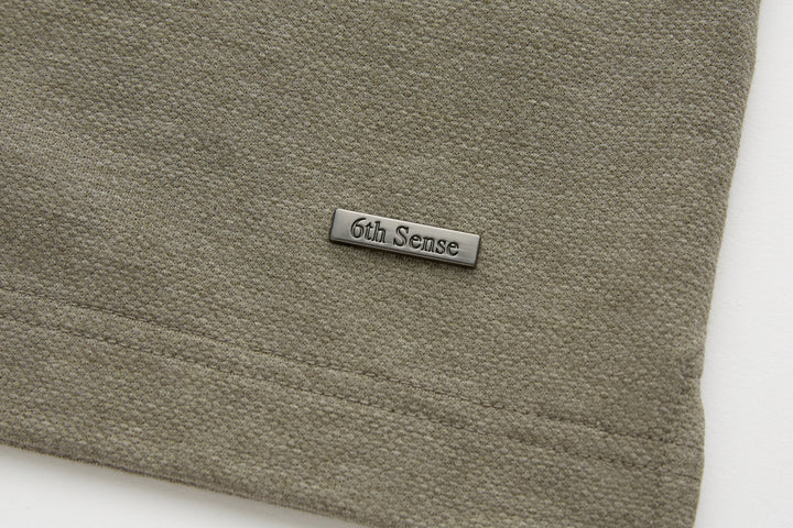 Olive polo shirt hem with 6th Sense logo label