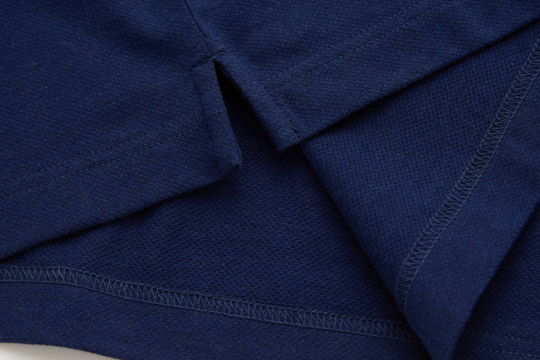 Dress blue polo shirt sleeve and hem seam close-up with visible stitching detail