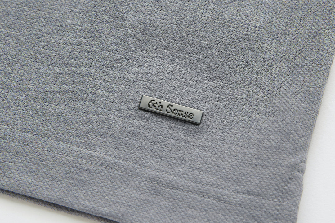Light gray polo shirt with stitched 6th Sense logo patch on chest