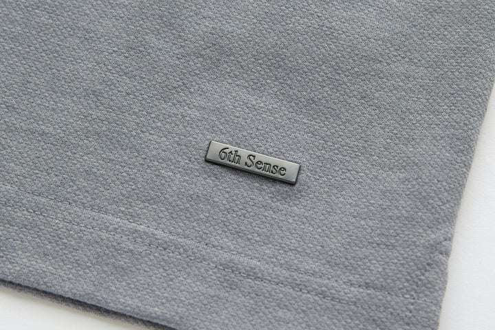 Light gray polo shirt with stitched 6th Sense logo patch on chest