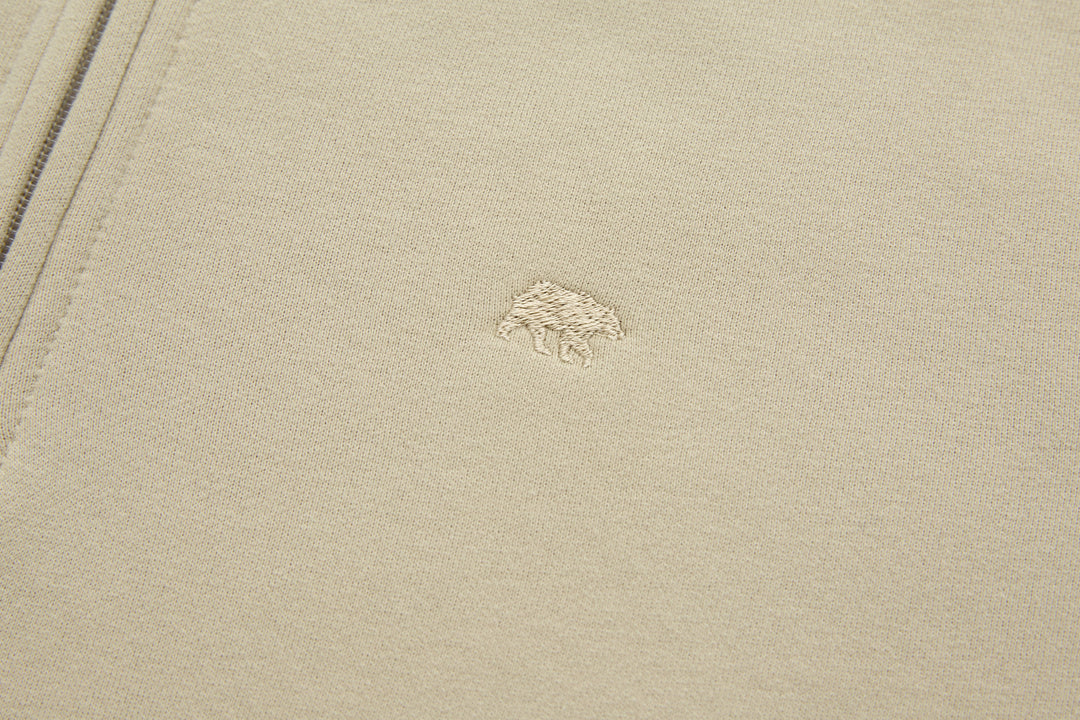 Beige 1/4-zip top with small embroidered logo on chest