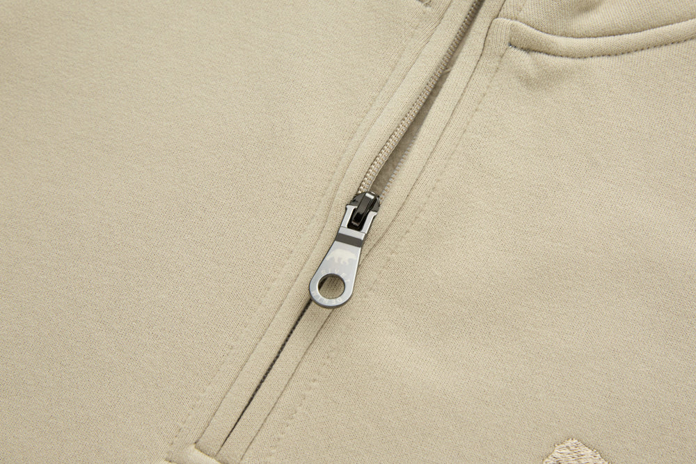 Beige 1/4-zip top with metal zipper and stitched placket